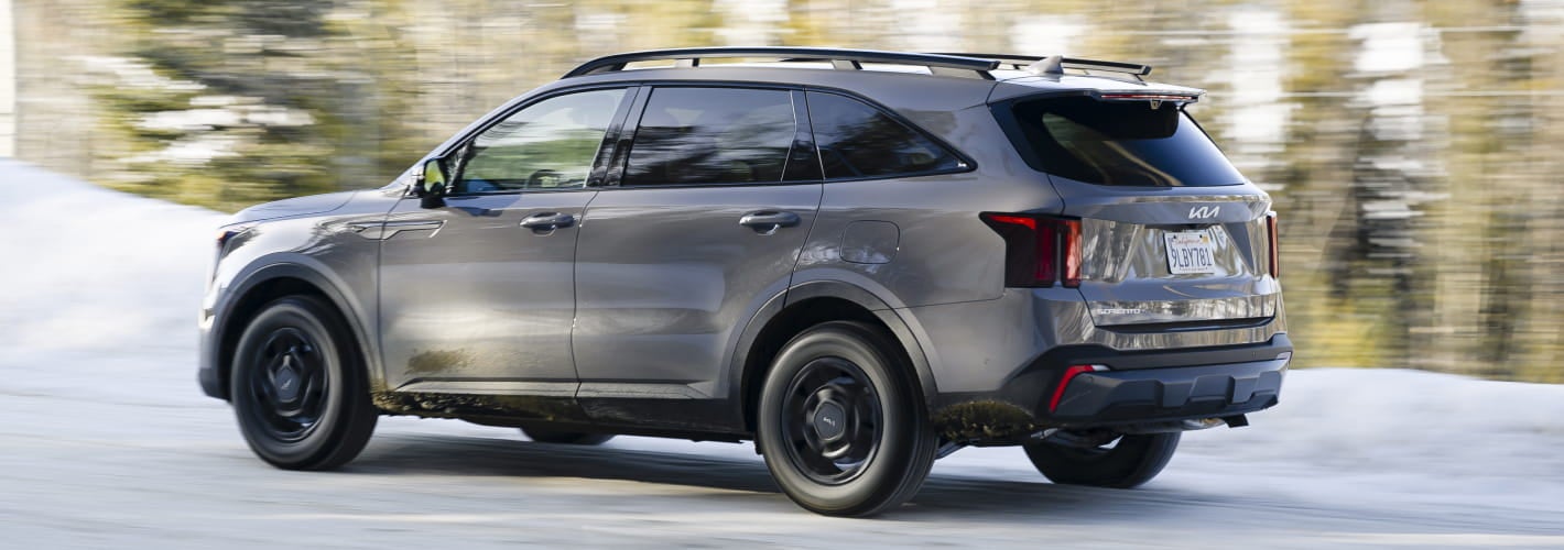 2026 Kia Sorento drives on a snowy road, surrounded by a blurred forest.