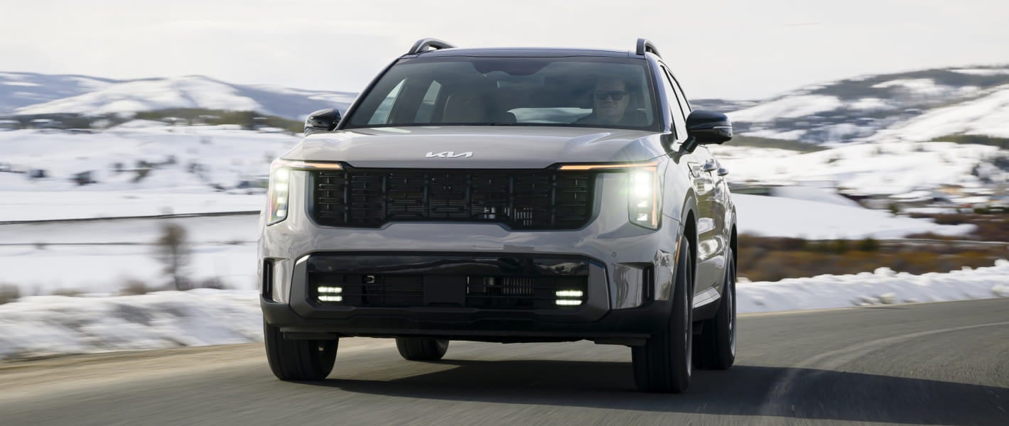 A sleek 2026 Kia Sorento drives on a snowy mountain road.